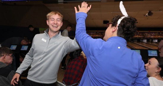 UNK junior Dylan Pfeifer celebrates with a Buddy Bowling participant during last week’s event at Big Apple Fun Center in Kearney. (Photo by Erika Pritchard, UNK Communications)