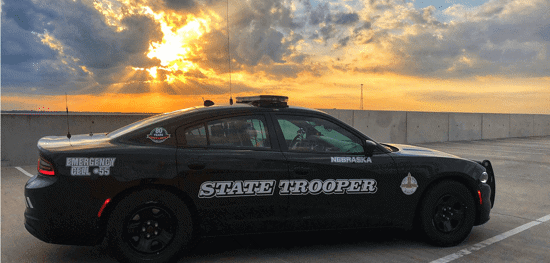 Passenger side of a Nebraska State Patrol Cruiser with a sun set in the background.